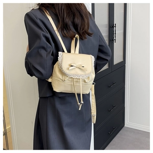 Back view of a beige mini bucket backpack with delicate lace trim and bow decoration