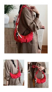 Detail of red crescent canvas bag with knotted rope shoulder strap and wooden bead charm