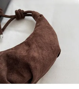 Detail view of the brown ruched cloud bag showing the soft suede texture and knotted strap