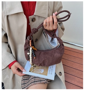 Detail of dark brown suede crescent bag with wooden beads and knotted shoulder strap