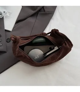 Detail of dark brown suede handbag interior showing capacity for cosmetics and phone