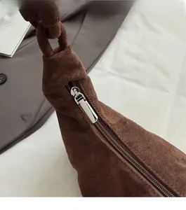 Detailed close-up of smooth silver zipper and soft brown suede texture on a cloud bag