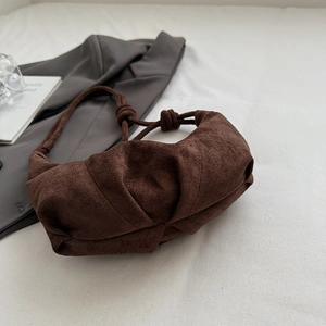 Detail of dark brown pleated cloud bag with knotted handle on minimalist fabric