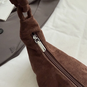 Detail of coffee brown suede cloud bag with silver zipper and unique knotted strap design