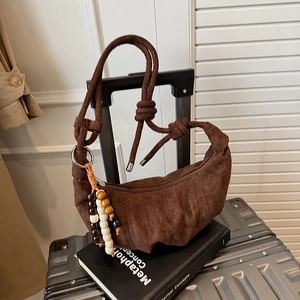 Detail of brown suede half-moon bag with knotted strap and wooden bead tassel accessory