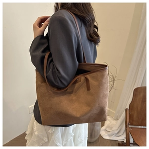 Detail der dunkelbraunen Wildleder-Tragetasche mit langen Riemen für einen minimalistischen Look