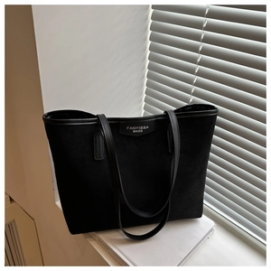 Detail of black tote bag with matte suede texture and polished faux leather trim accents
