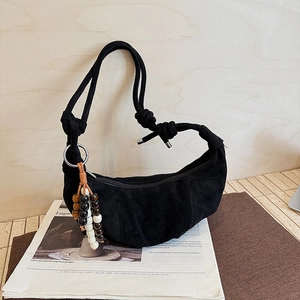 Detail of black crescent hobo bag featuring knotted strap and colorful beaded tassel charm