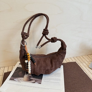 Detail of a brown suede crescent bag with pleats and vintage beaded charm ornament