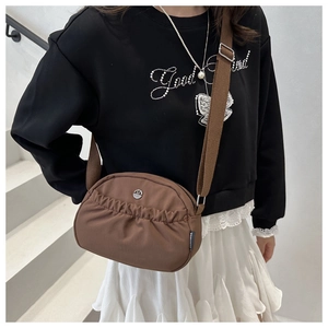 Close-up of brown nylon crossbody bag featuring ruffled design and adjustable wide strap