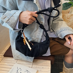 Detail of black cloud shoulder bag featuring knotted rope strap and colorful wooden beads