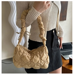 Detail of light khaki quilted shoulder bag with chic pleated ruched handle texture