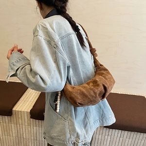 Detailed view of brown pleated croissant bag with soft suede texture on shoulder