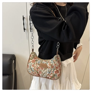 Detail of vintage floral embroidery on underarm bag with leather trim and gold chain strap