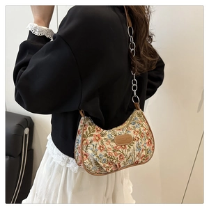 Detail of floral tapestry hobo bag with brown leather trim and metal chain strap