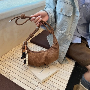 Close-up of brown suede moon bag with unique wood bead charm and knotted strap details