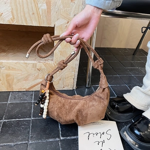 Detail of a brown suede hobo bag with knotted strap and colorful beaded tassel charm
