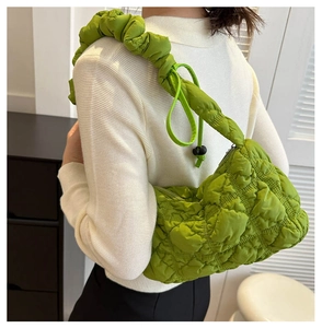 Détail d'un sac porté épaule matelassé vert avec bandoulière froncée sur une personne