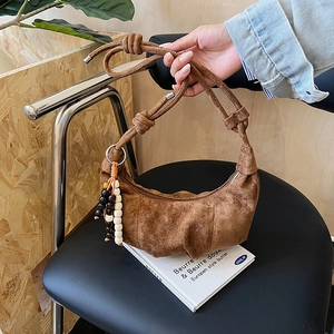 Detail view of brown suede crescent bag with knotted strap and colorful wooden beads