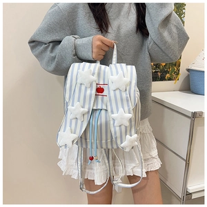 Detail of blue striped backpack featuring plush stars and red apple embroidery