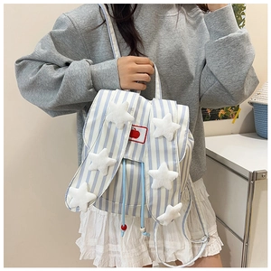 Detail of blue-white striped canvas backpack featuring bunny ears and plush star charms