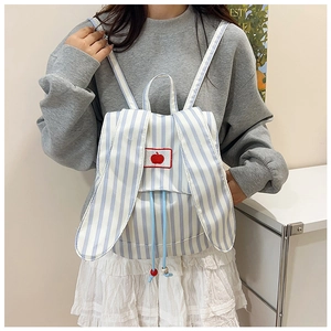 Détail du sac à dos en toile à rayures bleues avec oreilles de lapin et pomme brodée