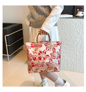 Detailed shot of tote bag with bamboo handles and red floral embroidery fabric