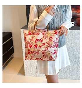 Close-up of pink silk tote bag with floral embroidery and natural bamboo handles