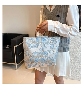 Close-up of blue floral jacquard tote bag with natural bamboo handles in lifestyle setting