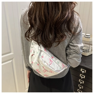 Détail du sac à bandoulière en nylon blanc avec motifs floraux et nœuds roses en situation