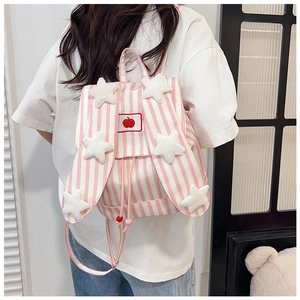 Detail view of pink striped backpack with plush stars and apple embroidery on a model