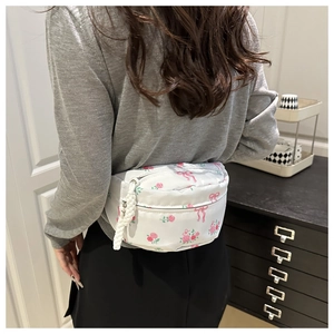 Gros plan d'un sac bandoulière en nylon à fleurs avec motifs roses et fermeture tissée