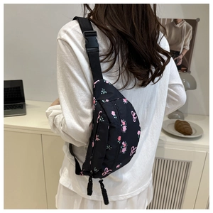 Détail de la bandoulière et boucle de la sacoche en nylon noir à motif floral pour femme