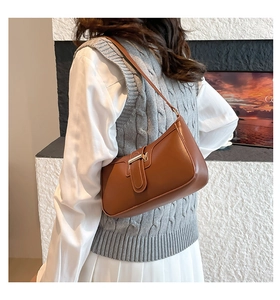 Detail of a brown French-style underarm bag featuring a gold metal buckle and leather strap