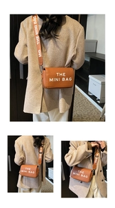 Close-up of brown leather mini crossbody bag with wide shoulder strap and white logo text
