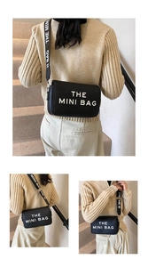 Detail view of black mini crossbody bag with wide strap and white lettering text