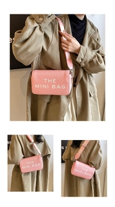 Macro detail of pink textured leather crossbody bag with wide logo strap and mini bag text