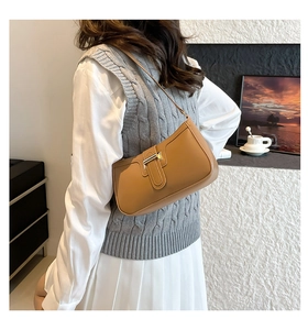Detail of a brown vintage baguette bag with matte leather finish and golden metal buckle