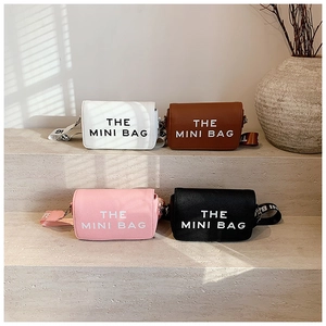Detailed view of four colorful mini square bags with wide patterned straps on stone steps