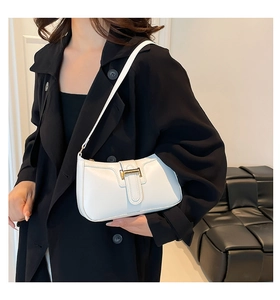 Close-up of white faux leather underarm bag with gold buckle on black blazer