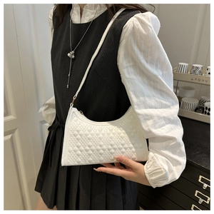 Close-up of a white shoulder bag featuring textured relief patterns and golden hardware