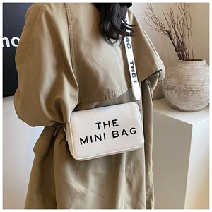 Close-up of a white lychee grain mini bag with The Mini Bag lettering and printed strap