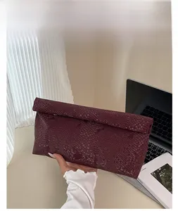 Detail of burgundy snakeskin texture on an envelope clutch bag for women