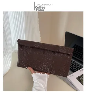 Detail of coffee brown snakeskin textured clutch bag with elegant metallic ring accent