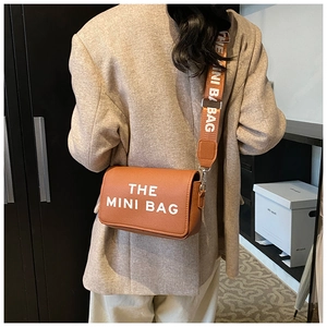 Detail of THE MINI BAG in orange pebble leather with wide branded textile strap
