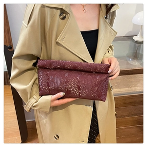 Detail of burgundy snakeskin patterned box bag held by model wearing a khaki coat