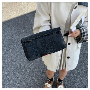 Detail view of the black snake skin texture and metal connector on this luxury clutch bag