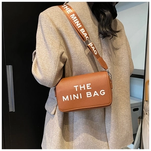 Brown litchi leather mini crossbody bag with a wide branded shoulder strap on model