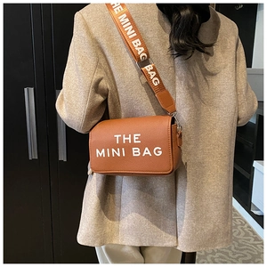 Rear view of model wearing a brown leather mini bag with white text and wide strap