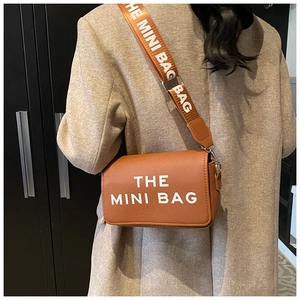 Brown lychee leather mini crossbody bag featuring wide strap with The Mini Bag text